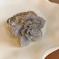 Close-up detail of a luxury rhinestone-encrusted flower on an adjustable vintage bangle. - Silver
