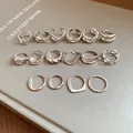 Detailed view of multiple minimalist silver geometric open rings on a gray background - Style 8