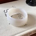 Dettaglio di un bracciale bianco irregolare dal design minimalista con finitura liscia - Bianco latte