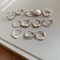 Collection of silver irregular geometric open rings displayed on a sleek grey book cover - Style 6