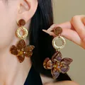 Vista dettagliata di orecchini a fiore in ambra retrò con anelli dorati sul modello - Design n. 17 / Perno in argento 925 / Regular Brown Gold