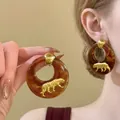 Primo piano di orecchini a cerchio leopardati retrò con pantera dorata indossati sul modello - Design n. 18 / Perno in argento 925 / Marrone oro
