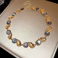 Vintage resin necklace featuring iridescent blue stones and gold-toned textured metal links. - Necklace / Gold Grey