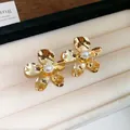 Elegante goldene Blumenstecker mit einer Perle in einem Schmuckdisplay ansprechend präsentiert - Wellenförmiger Perlenblumenstil (29#)