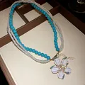 Close-up detail of vintage flower pendant necklace with white pearls and turquoise beads - Necklace