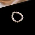 Minimalist elastic pearl ring with white lustrous beads on black velvet background - Style 18 (HR1941)