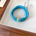 Detail of a vintage multi-strand turquoise beaded necklace with a gold centerpiece. - Bracelet