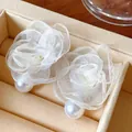 Macro detail of elegant white mesh flower earrings with faux pearl accents on jewelry tray - White