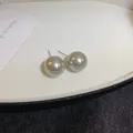 Detalle en primer plano de pendientes de perlas grises en una bandeja de exhibición blanca - Estilo Aguja de Plata Gris / 12mm