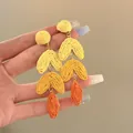 Hand-held detail of yellow and orange raffia woven gradient drop earrings for vacation. - Gradient Long Woven Style (11#)