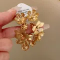Vue détaillée des boucles d'oreilles fleurs dorées vintage avec étiquette en argent 925 - Or