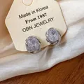 Close-up of elegant 18k gold-plated geometric zircon clip-on earrings on display card - Geometric Round Ear Clip / Silver
