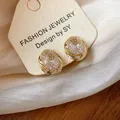 Macro detail showing 18k gold plated geometric zircon ear clips on a luxury display card - Geometric Round Ear Clip / Gold