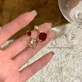 Close-up of elegant asymmetrical earrings with red stones and square zircons - Red & Gold Asymmetrical