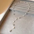 Detailaufnahme einer Perlenkette mit geometrischen Silberakzenten auf einem grauen Tablett - Halskette / Silber