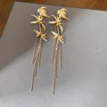 Elegant gold bamboo leaf dangle earrings with long beaded tassels on grey background - Gold
