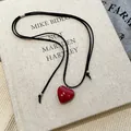 Detail view of a vibrant red resin heart pendant on a minimalist adjustable black cord - Heart Pendant (HN7501) / Adjustable Cord / Red