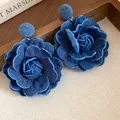 Primo piano macro della trama degli orecchini a fiore in tessuto denim blu scuro - Versione Grande / Perno in argento 925 / Blu