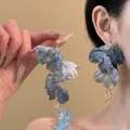 Detailansicht blauer geflochtener Blumenohrringe mit Kristallquasten an einem Model - Farbverlauf Blauer Gestaffelter Blütenblattstil (11# Silberstift)