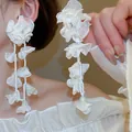 Makro-Detailansicht der langen weißen Raffia-Blumenohrringe mit zarten Perlen - Weißer Statement Stoff Quastenstil (13# Silberstift)