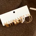 Detail shot of a vintage gold earring set with pearls and twisted hoops on a textured background. - Gold / 12pcs Set
