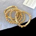 Set of elegant stackable gold beaded and tube bracelets for a layered jewelry look - Metal Tube Beaded Style / Five-Piece Set / Gold