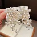 Close-up of elegant flower-shaped pearl tassel earrings with silver needles and luster. - White