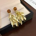 Detailed macro view of vintage gold leaf tassel earrings with round amber-colored beads - Silver Pin Resin Ball Leaf Tassel Two-Way Wear Earrings