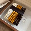 Primo piano del bracciale bohémien multistrato in grani di legno in una scatola portagioie - Bianco-Caffè