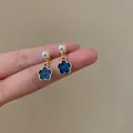 Dettaglio di orecchini retrò francesi con fiori blu Klein ed eleganti perle lucide - Fiore Blu