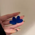 Primo piano di orecchini a cuore blu Klein retrò con texture vellutata su perni in argento - Cuore blu