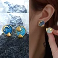 Detailed view of asymmetrical celestial sun and moon stud earrings with blue enamel. - Blue & Gold Asymmetric (Style 22)
