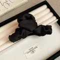 Close-up of black fabric hair claw clip with delicate rhinestone embellishments in a tray - Black