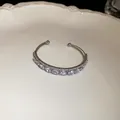 Close-up view of an elegant double-layer open bangle featuring pear-shaped clear zircons - Water Drop / Silver