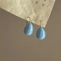 Detailed close-up view of light blue teardrop oil-drop earrings with gold ear hooks - Earring Hooks / Blue