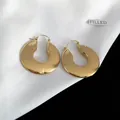 Dettaglio di orecchini a cerchio geometrici spessi in acciaio dorato su tessuto di seta - Stile Geometrico a U / Oro