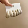 Primo piano dettagliato di sei orecchini a cerchio in resina con trama marmorea. - Aghi In Acciaio N. 8 - Bianco Sporco (set Da 6 Pezzi)