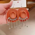 Dettaglio di orecchini creativi a forma di cappello da cowboy arancione con strass - Stile Gancio / Marrone