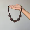 Retro style dark brown wooden bead necklace featuring large round flat pendants displayed by hand - Retro Ethnic Wood Beaded Long Necklace