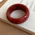 Detailed macro view of a vintage red marbled resin bangle resting on a beige book - Round Wide Bangle / Brown