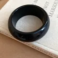 Detail shot of a retro minimalist thick black glossy circular bangle on a vintage book - Round Wide Bangle / Black