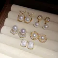 Vista dettagliata di cinque paia di orecchini vintage in perle e strass dorati in un vassoio. - 25# Perno d'argento - Oro