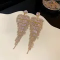 Close-up of sparkling heart-shaped tassel earrings featuring brilliant cubic zirconia details. - Heart Tassel Style / Gold