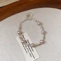 Close-up of elegant French style zircon pearl bracelet on a cream textured fabric background - Adjustable Drawstring / Silver-Pink