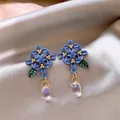 Exquisite close-up of blue floral stud earrings with elegant clear crystal teardrop dangles - Blue