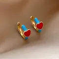 Detail of gold hoop earrings featuring vibrant red and blue enamel heart charms - Blue