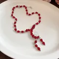 Primer plano de un collar de capullos de resina roja con piedra blanca en un plato blanco. - Solo Collar / Rojo