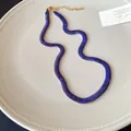 Primer plano del collar gargantilla azul con patrón de piel de serpiente y cierre dorado. - Azul