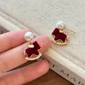 Primer plano de pendientes de caballo balancín flocados rojos con perlas - Estilo Caballo Balancín / Dorado-Rojo
