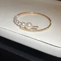 Close-up detail of an elegant gold open bangle featuring graduated pearls and fine rhinestones - Style 3